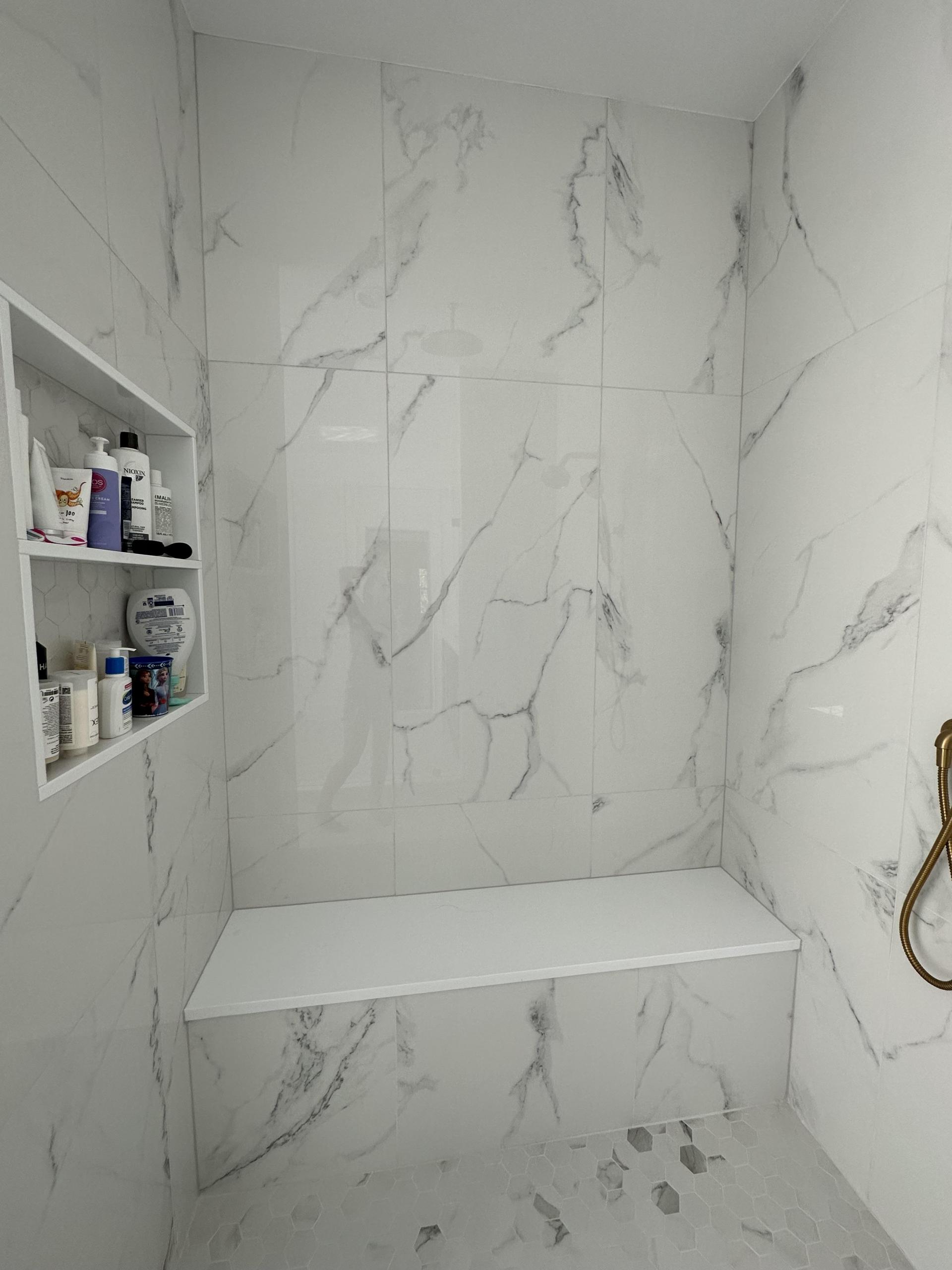 Products featured: 12x24 Lustre Calacatta Polished set on a herringbone, 24x48 Lustre Calacatta Polished, 24x48 Shower walls, and 2x3 Hex Carrara Hex Matte niche. Joe Limiero in our West Hartford showroom.