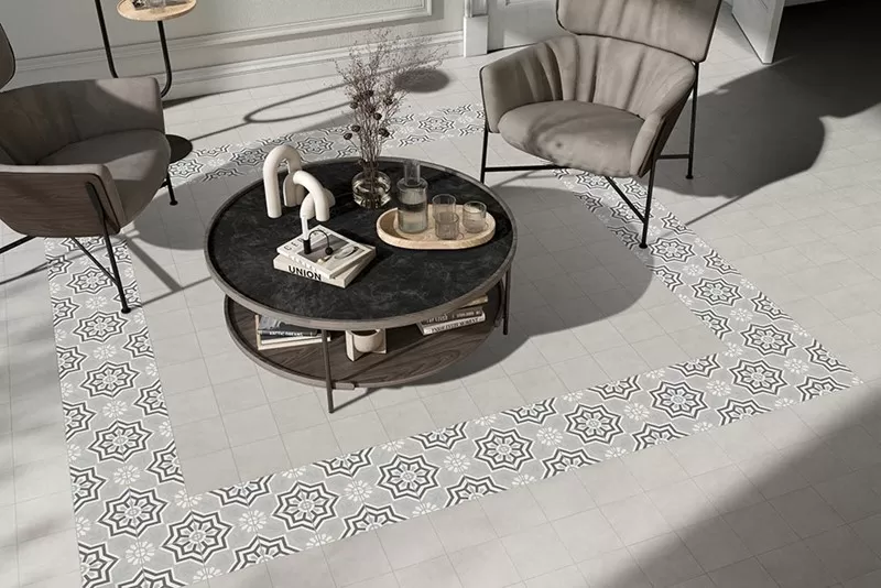 Sitting area with a table and two chairs. Floor has a grey and pattern tile.