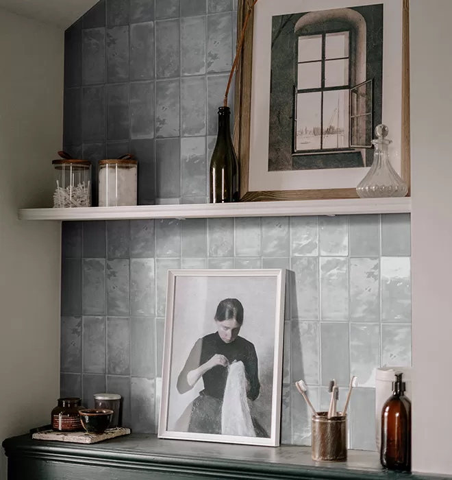 Tile arched wall with shelves. Picture frames and knickknacks on the shelves.