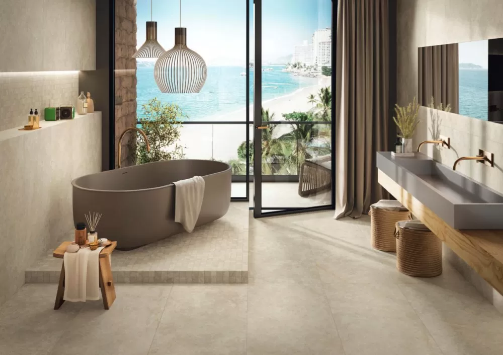 Beige wall and floor bathroom with taupe bathtub and sink with big window with beach view.