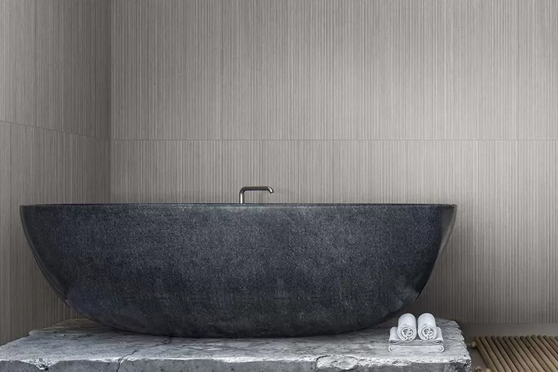 bathtub in front of a beige tiled wall