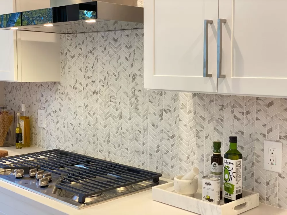 Kitchen backsplash with a fake marble chevron  and a stove top range