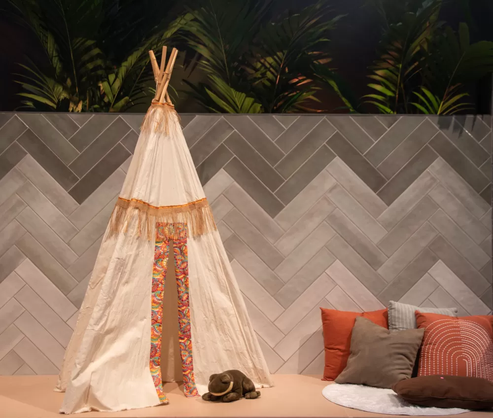 Multicolored wall with a teepee and some pillows on the floor.